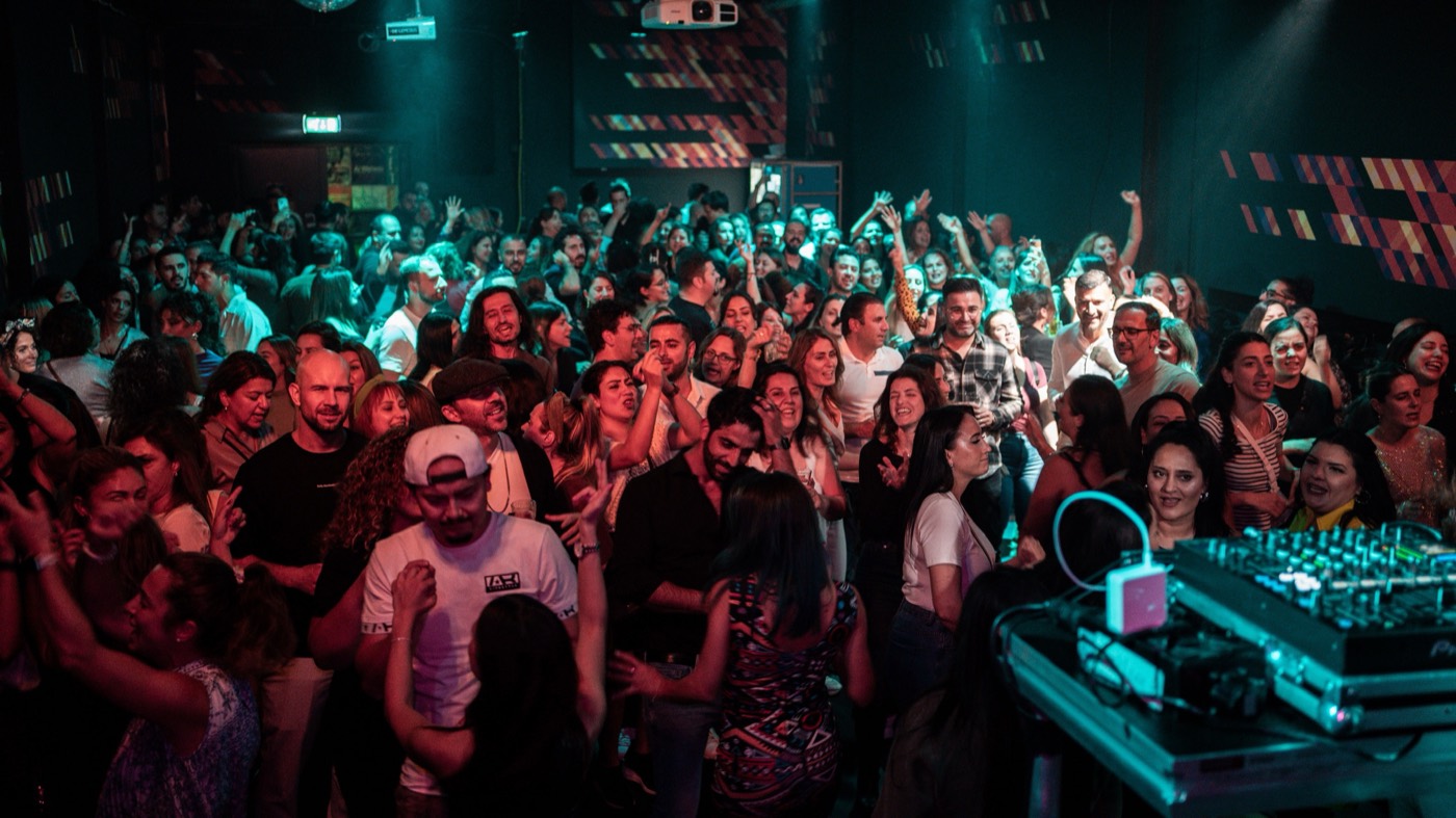 Crowd dancing under green lights at a Turkish Pop Night